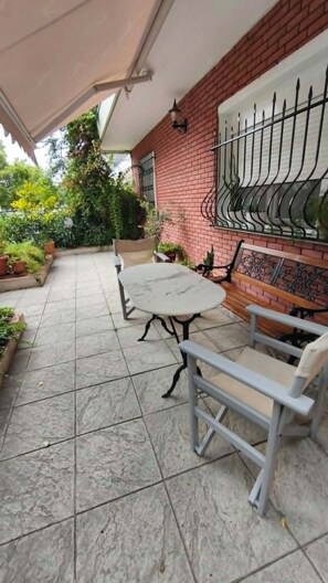 An outdoor patio with a round table and chairs, a brick wall, and a metal railing.