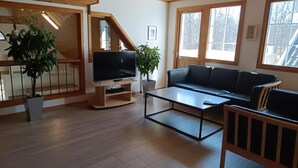 A modern living room with a flat-screen TV, a sofa, a coffee table, and two potted plants. - VillaVilla 127 - Öland, Sverige (Köpingsvik)
