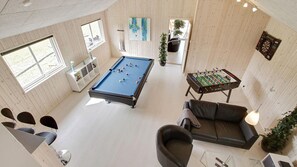 Um quarto espaçoso com mesa de bilhar, mesa de futebol de mesa e um sofá.