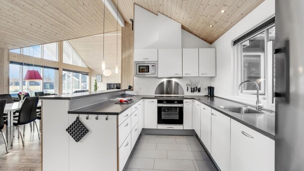 A modern kitchen with white cabinets, a built-in oven, and a large window. - VillaVilla 299 - Marielyst, Lolland/Falster/møn (Idestrup)