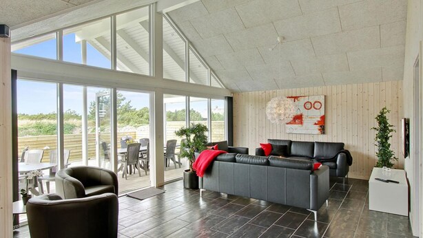 Een ruime woonkamer met een grote bank, een eettafel en stoelen.