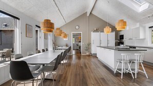 Een moderne keuken met witte kastjes, een centraal eiland en hanglampen.