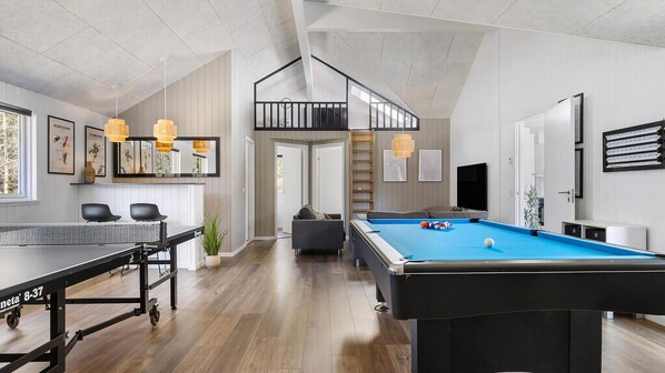 Un salon moderne comprenant une table de billard, un canapé et un coin repas avec une table et des chaises.