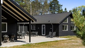Une cabane à deux étages dotée d’un patio aménagé avec du mobilier d’extérieur et un barbecue.
