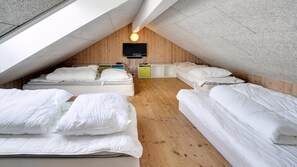 Ein Schlafsaalzimmer mit Etagenbetten, einem Fernseher und einem kleinen Schrank.