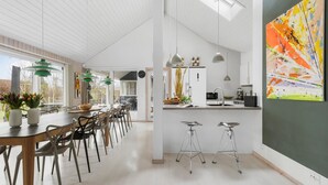 A modern kitchen with white cabinetry, pendant lighting, and a large abstract painting on the wall.