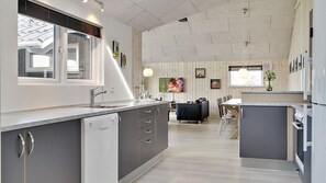 A modern kitchen with grey cabinets, a built-in dishwasher, and a large window.