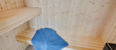Un sauna avec des murs en bois et un banc.