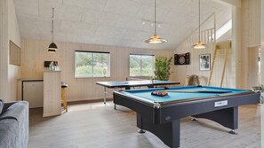 A pool table in a room with wooden walls and a ceiling with exposed beams.