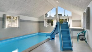 A swimming pool with a blue slide, a ladder, and a chair.