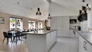 Una cucina moderna con isola centrale, mobili bianchi e luci a sospensione.