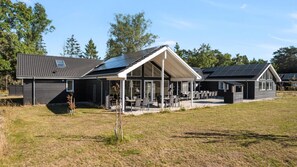 Une maison moderne dotée d’un patio couvert, d’un coin repas séparé et d’un toit équipé de panneaux solaires.