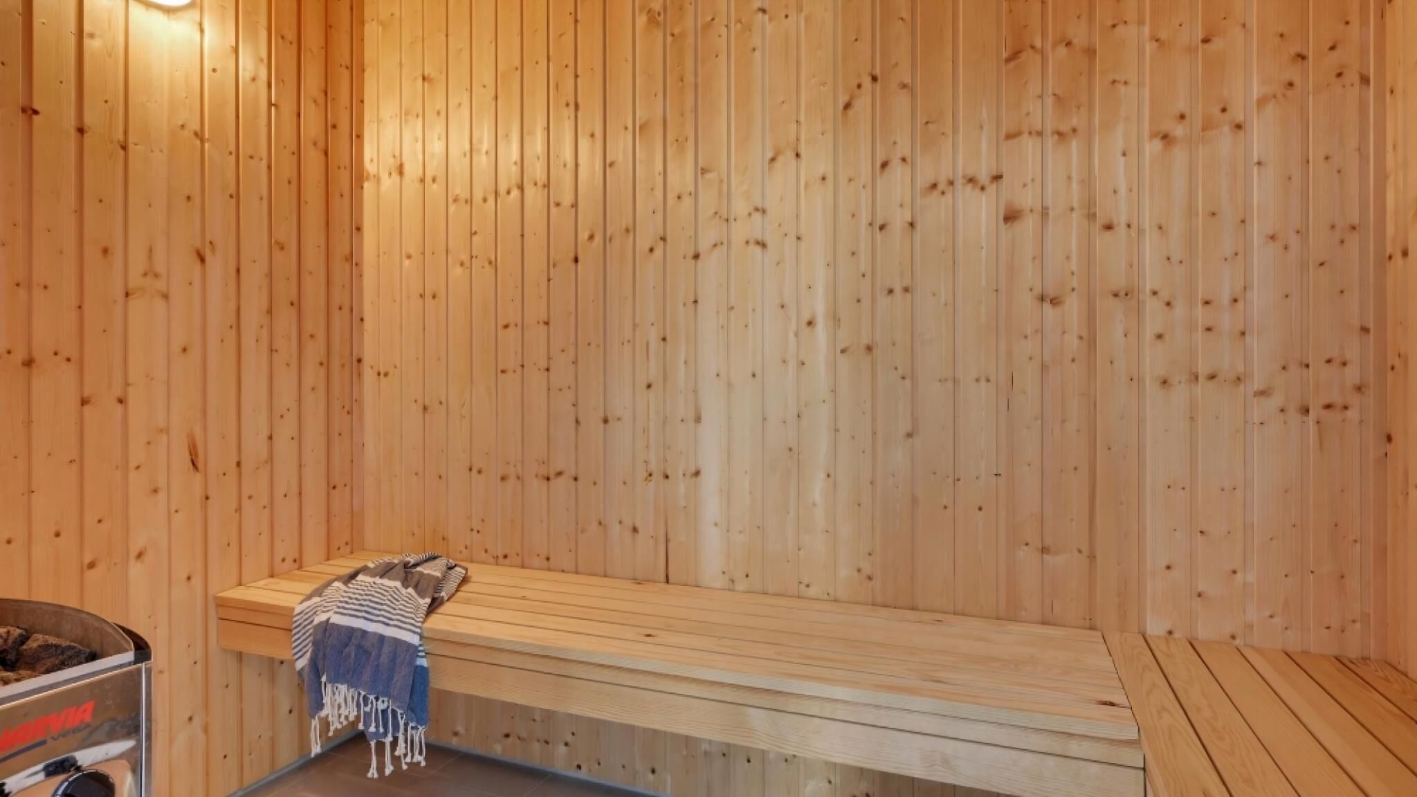 Een sauna met houten wanden en banken, een bank met een handdoek, en een sauna-kachel.
