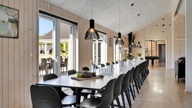 A long dining table with chairs, pendant lights, and a view of the outdoors. - VillaVilla 436 - Asserbo/Liseleje, Nordsjælland (Frederiksværk)