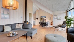 Een moderne woonkamer met een grijze modulaire bank, een salontafel, en een eethoek met een tafel en stoelen.