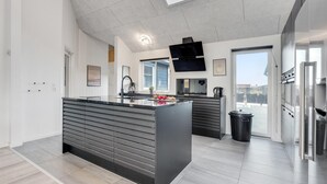 A modern kitchen with a central island, built-in appliances, and a large window providing natural light. - VillaVilla 486 - Bjerregård, Vestjylland (Hvide Sande)