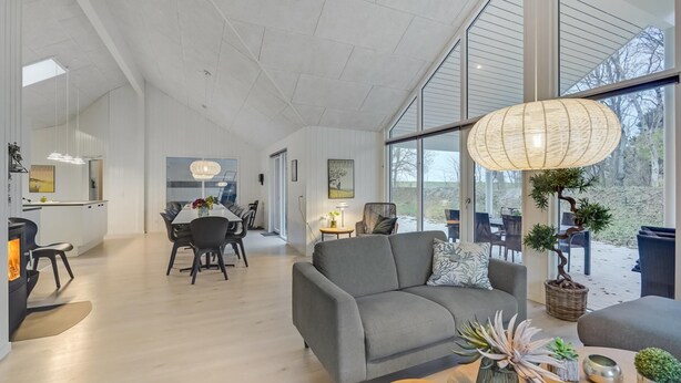 A spacious living area with a dining table, sofa, and large windows offering a view of the outdoors.