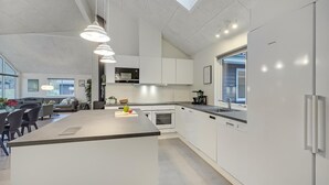 A modern kitchen with a central island, white cabinetry, and a built-in oven.