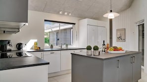 Une cuisine moderne dotée d’un îlot central, d’appareils électroménagers intégrés et d’une grande fenêtre.