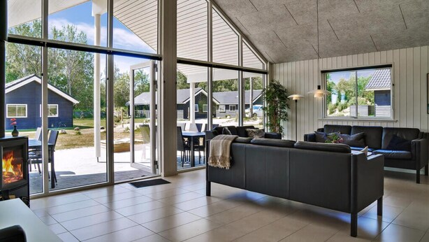 A spacious living area with a large glass door leading to an outdoor patio, a fireplace, and a cozy seating area. - VillaVilla 503 - Marielyst, Lolland/Falster/møn (Væggerløse)