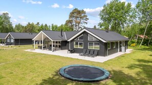 Une propriété résidentielle dotée d’un patio couvert, d’un trampoline et d’une grande pelouse.