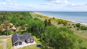A house with a large deck and a trampoline, surrounded by trees and a beach. - VillaVilla 503 - Marielyst, Lolland/Falster/møn (Væggerløse)