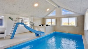 Ein hallenbad mit einer blauen Rutsche, ein sonnendurchfluteter Raum mit einem Fenster und Blick auf die Wüste.
