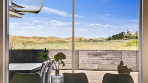 Eine Terrasse mit Blick auf ein Wiesfeld und Hügel.