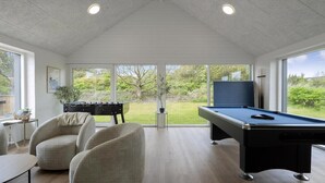 Een moderne ruimte met een pooltafel, een tafelvoetbalspel en comfortabele zitplaatsen.
