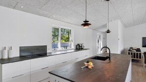 Een moderne keuken met een groot eiland, witte kasten en hanglampen.