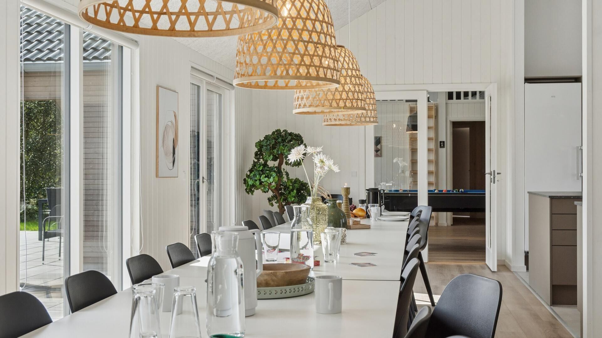 Een moderne eethoek met een pooltafel, eetstoelen en hanglampen.