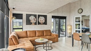 A modern living room with a sectional sofa, a round coffee table, and a dining area with chairs and a table.