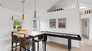 Une table de billard avec de longues bandes, un coin repas avec des chaises, un miroir et deux tableaux encadrés accrochés au mur.