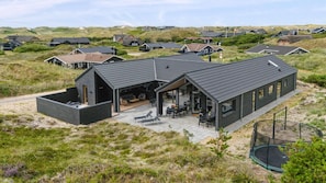 A modern house with a large patio, a swimming pool, and a view of the surrounding landscape.