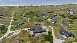 Vista aérea de una zona residencial costera con casas, caminos y una playa.
