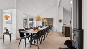 Un comedor moderno con una mesa larga, sillas negras y lámparas colgantes.