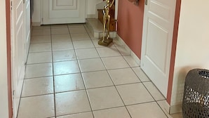 A hallway with a white door, a stained glass window with floral design, a golden statue, and a wicker basket. - Pleasant family home near Pézenas (Caux)