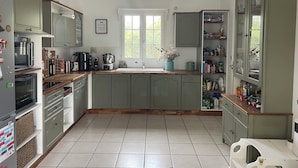 A kitchen with a large island, built-in appliances, and ample storage cabinets. - Pleasant family home near Pézenas (Caux)