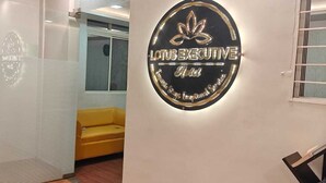 Interior de un hotel con una recepción, un sofá amarillo y un letrero en la pared para el Hotel Lotus Executive.
