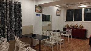 Una habitación con una mesa de comedor, sillas blancas, un mantel rojo cubriendo la mesa y un letrero de 'No Fumar'.