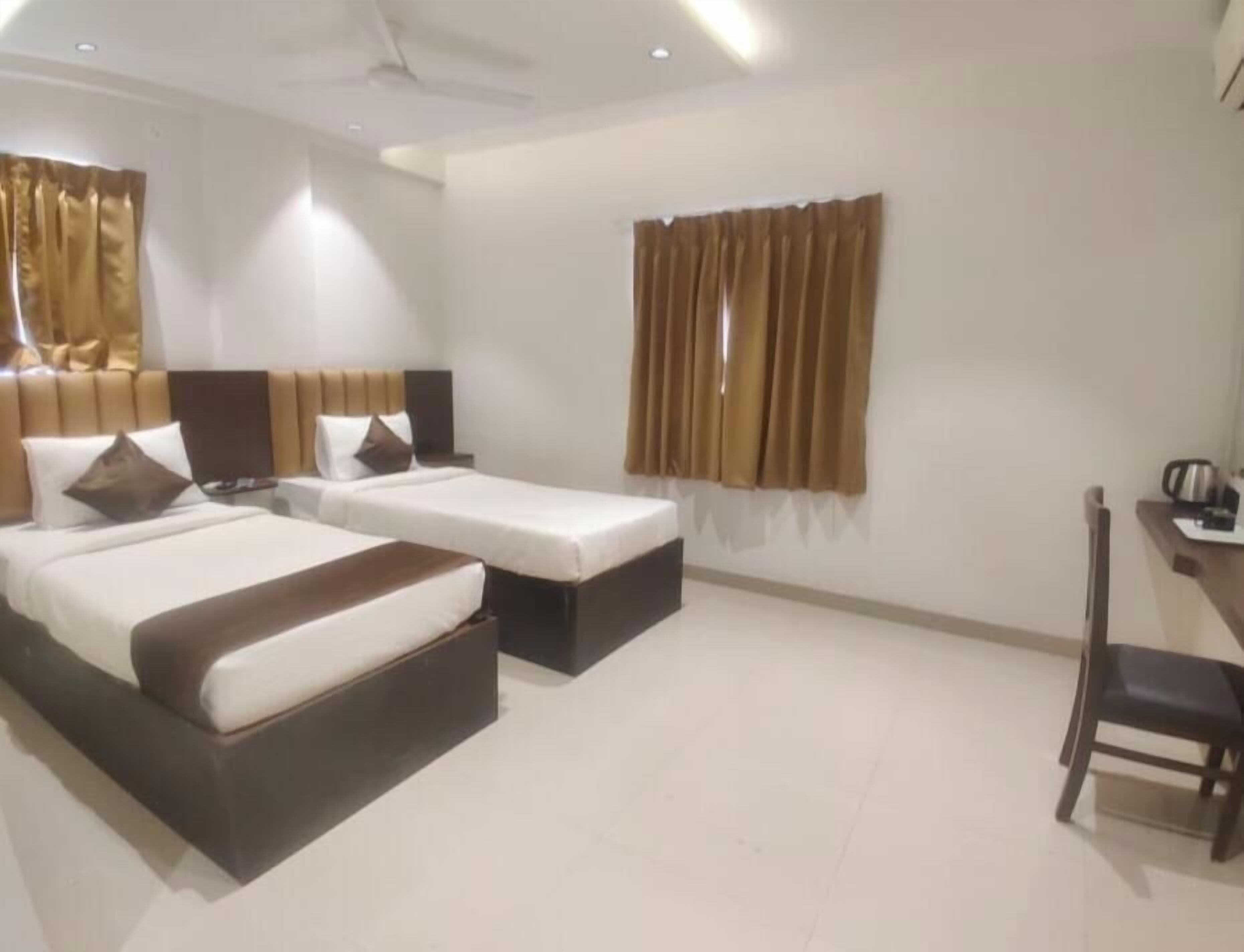 Une chambre d’hôtel avec deux lits, un bureau et une chaise.