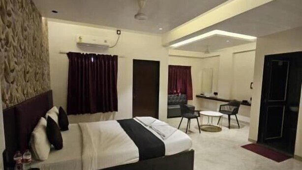 Una habitación de hotel moderna con una cama grande, un área de comedor y un baño separado.