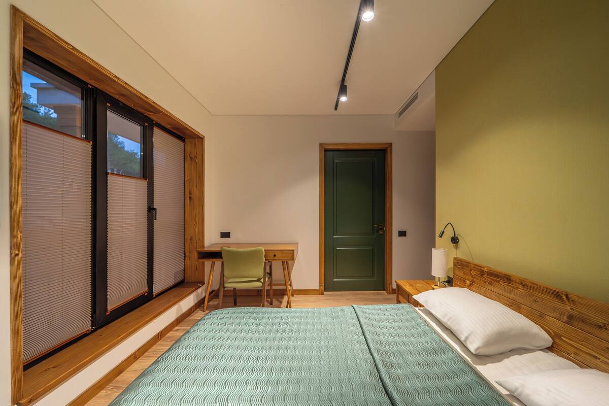 A bedroom with a bed, a desk, and a chair.