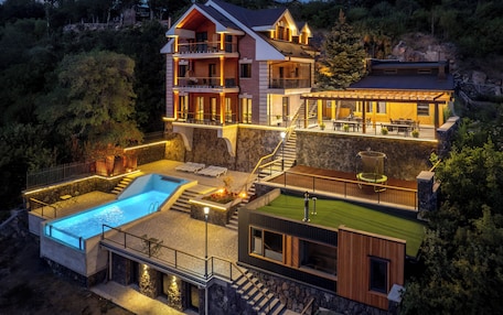 A multi-level house with a swimming pool, outdoor seating, and a stone retaining wall.