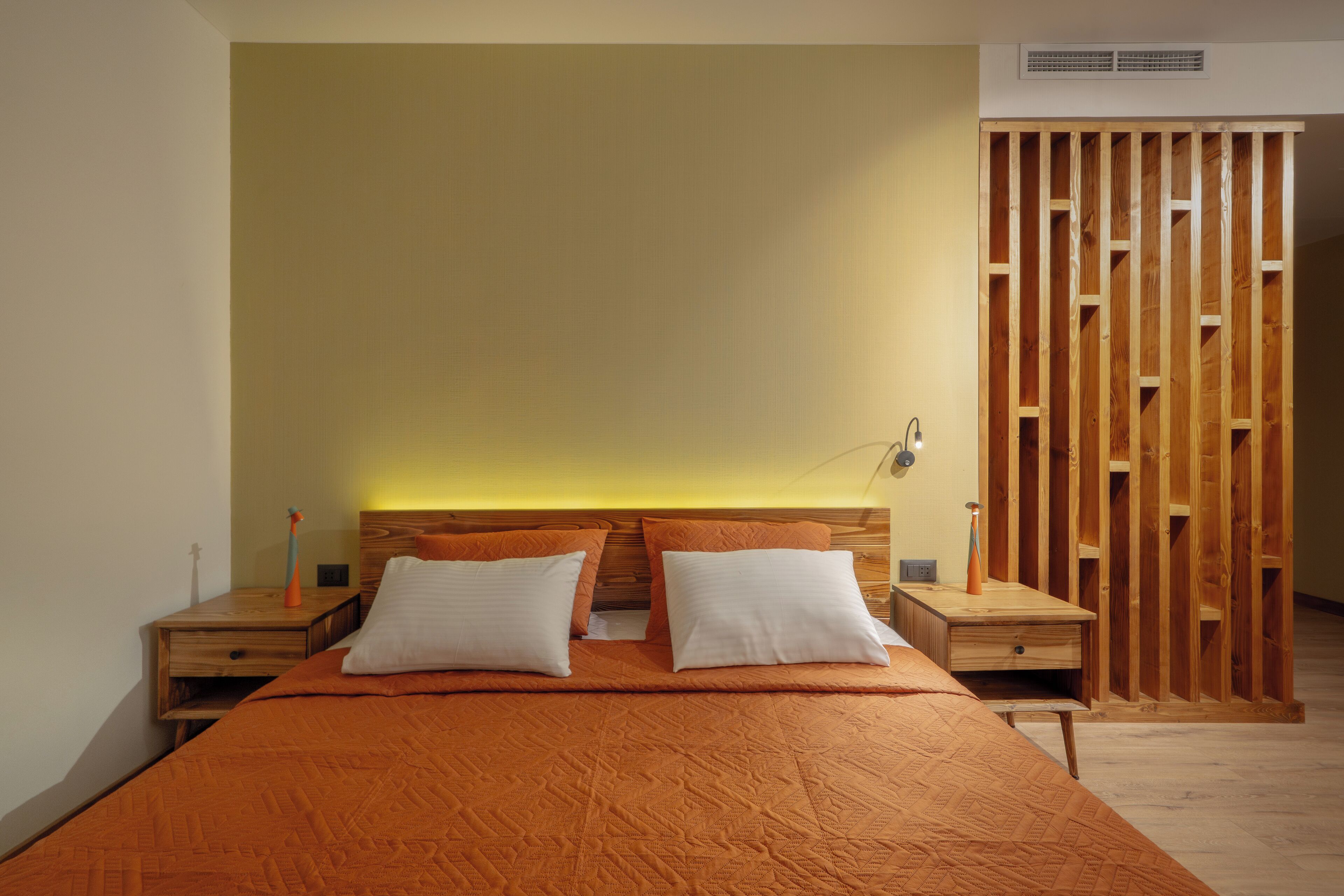 Une chambre avec un grand lit, deux tables de chevet et une cloison en bois.