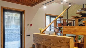 Un interior moderno con una escalera de madera, una computadora portátil sobre un escritorio de madera y una estantería.