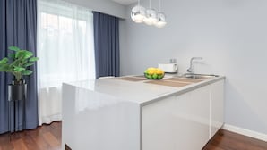 A modern kitchen with a central island, a sink, and a potted plant. - Modern Apartment | Private Garden and Parking (Gdańsk)