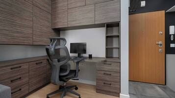 A modern office space with a desk, chair, computer, and built-in cabinets.