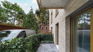 Un bâtiment moderne avec une façade en briques, un chemin pavé et une voiture garée dans l’allée.
