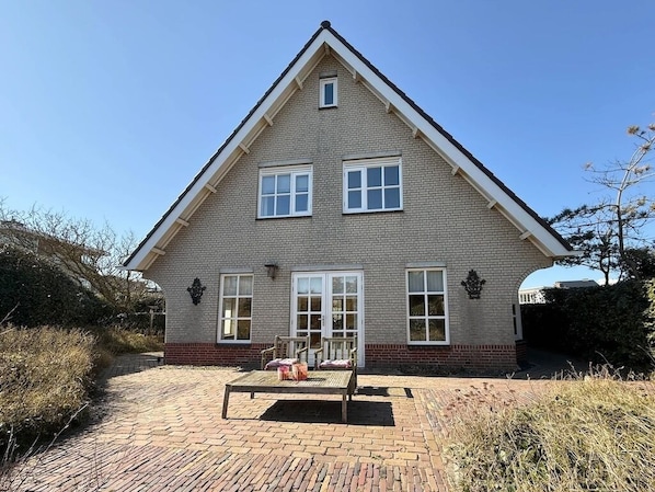 A two-story house with a brick exterior, white trim, and a central entrance.
